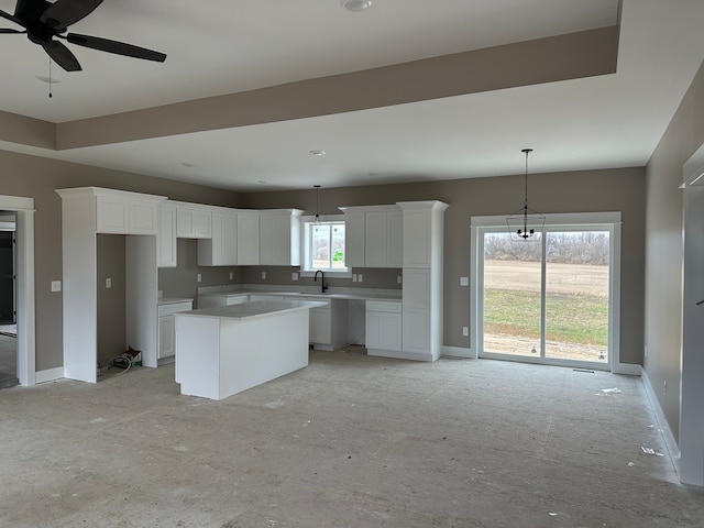 kitchen featuring decorative light fixtures, sink, a kitchen island, and white cabinets