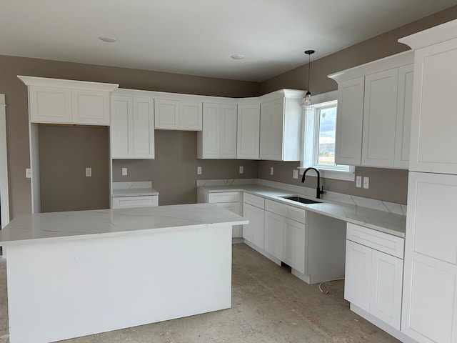 kitchen featuring pendant lighting, white cabinetry, a kitchen island, and sink