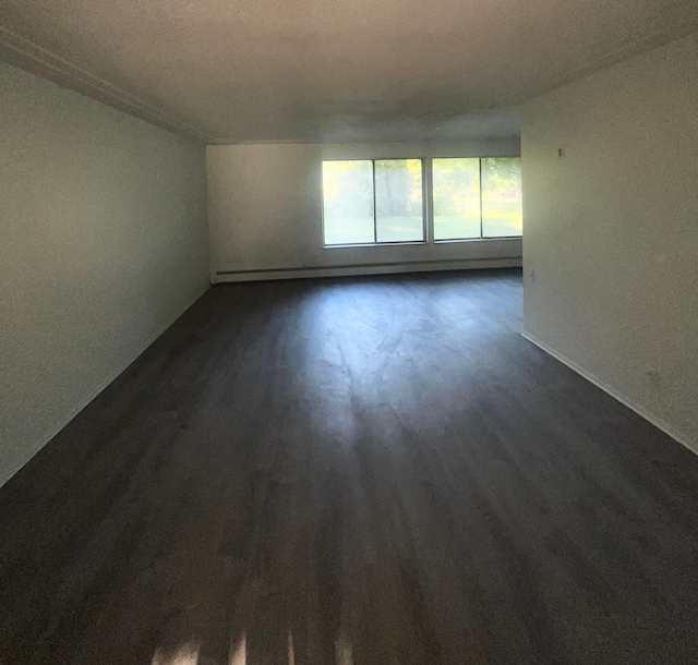 spare room with dark hardwood / wood-style floors and baseboard heating