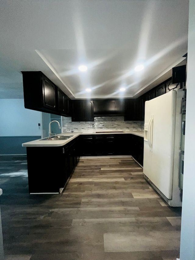 kitchen with backsplash, white fridge with ice dispenser, hardwood / wood-style floors, and sink