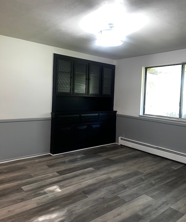 unfurnished room with a textured ceiling, dark hardwood / wood-style flooring, and baseboard heating