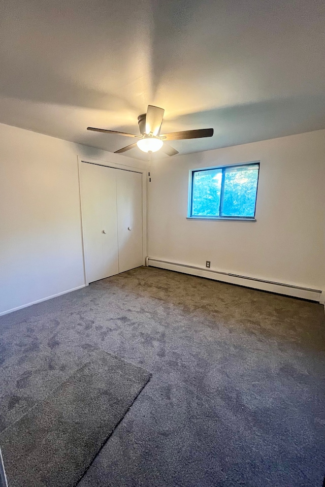 unfurnished bedroom with a closet, ceiling fan, dark colored carpet, and a baseboard heating unit