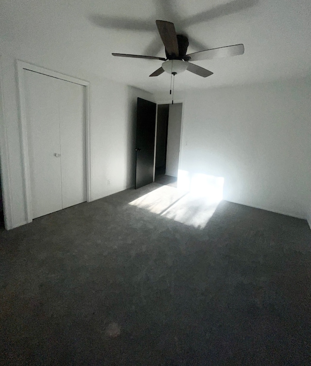 unfurnished bedroom featuring ceiling fan and dark colored carpet