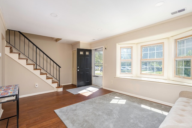 entryway with ornamental molding and dark wood-type flooring