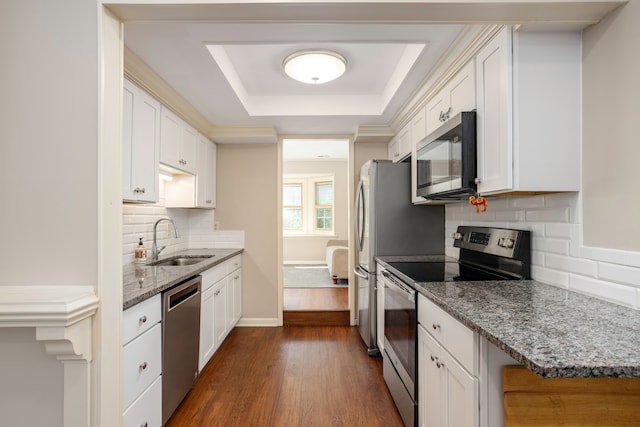 kitchen featuring appliances with stainless steel finishes, light stone counters, dark wood-type flooring, sink, and white cabinets