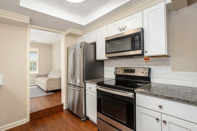 kitchen with appliances with stainless steel finishes, backsplash, dark stone countertops, white cabinets, and dark hardwood / wood-style floors