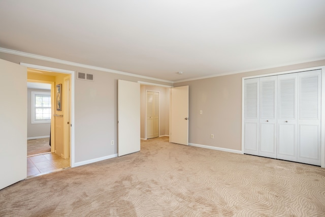 unfurnished bedroom with crown molding, a closet, and light colored carpet