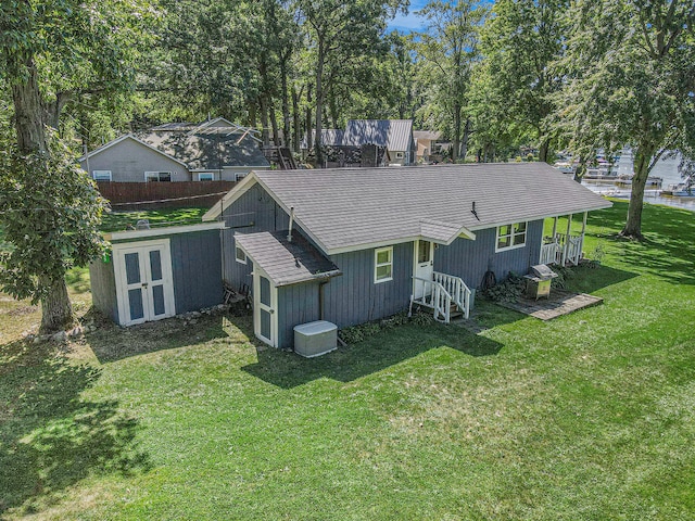 rear view of property with central AC unit, a storage shed, and a lawn