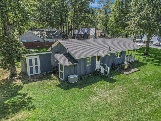 3055 E Baseline Rd, Gobles, MI 49055 - back of house with a lawn, a shingled roof, and view of scattered trees