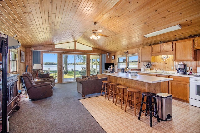 kitchen with ceiling fan, lofted ceiling, a breakfast bar area, light carpet, and wood ceiling