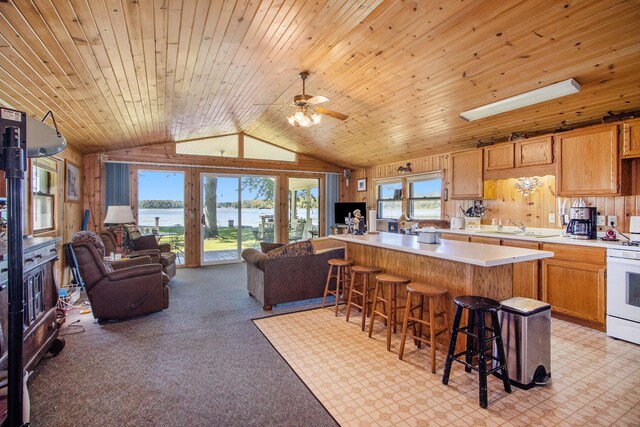 3055 E Baseline Rd, Gobles, MI 49055 - kitchen featuring white range with gas cooktop, a sink, a breakfast bar area, vaulted ceiling, and light countertops