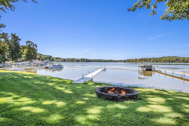 view of dock featuring a yard, a water view, and an outdoor fire pit