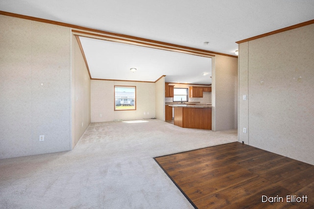 unfurnished living room featuring dark colored carpet and crown molding