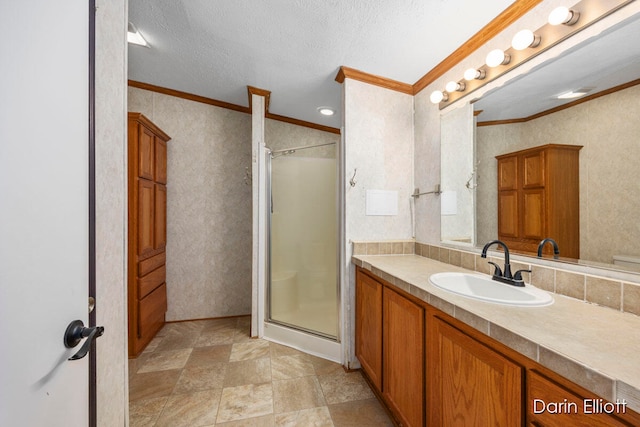 bathroom featuring crown molding, vanity, a shower with door, and a textured ceiling