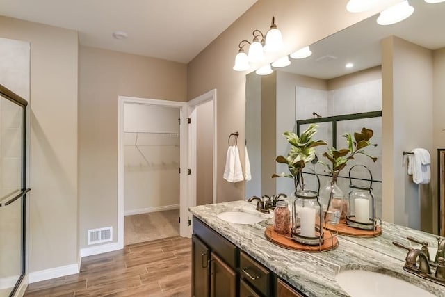 bathroom featuring a shower with shower door, vanity, and a notable chandelier