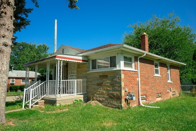 rear view of property featuring covered porch and a lawn