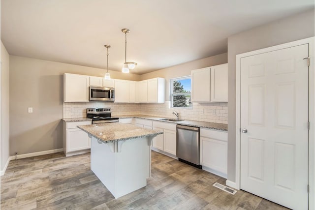 kitchen featuring a center island, white cabinets, hanging light fixtures, and appliances with stainless steel finishes