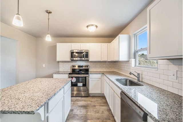 kitchen featuring white cabinets, stainless steel appliances, hanging light fixtures, and sink