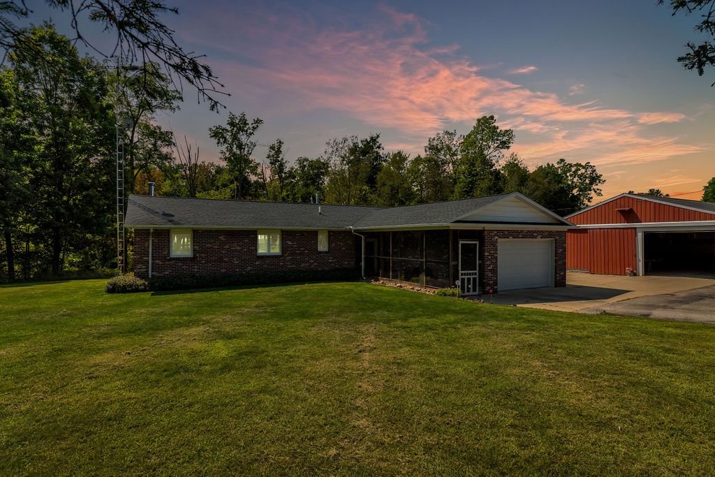 ranch-style home featuring a sunroom, an outdoor structure, a garage, and a yard