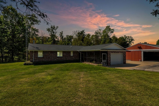 ranch-style home featuring a sunroom, an outdoor structure, a garage, and a yard