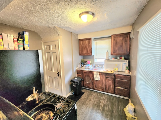 kitchen with hardwood / wood-style floors, plenty of natural light, a textured ceiling, and fridge