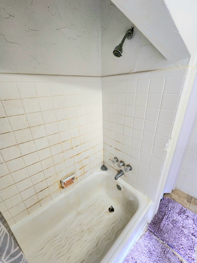 bathroom with tiled shower / bath combo and tile walls