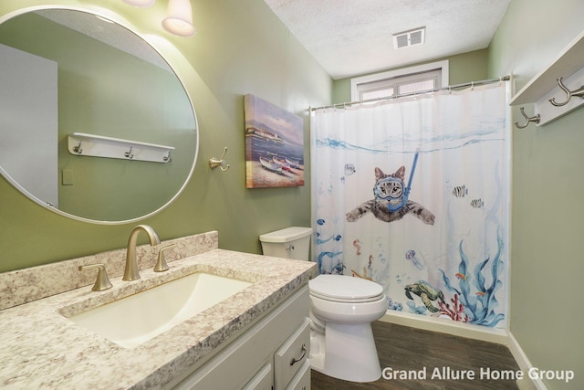 bathroom featuring wood-type flooring, vanity, walk in shower, toilet, and a textured ceiling