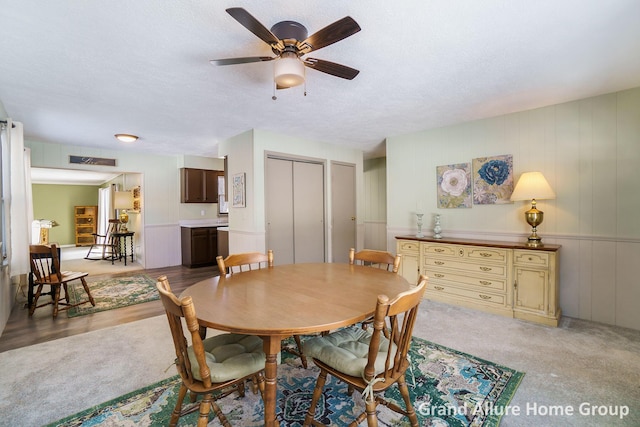 carpeted dining space featuring ceiling fan and a textured ceiling