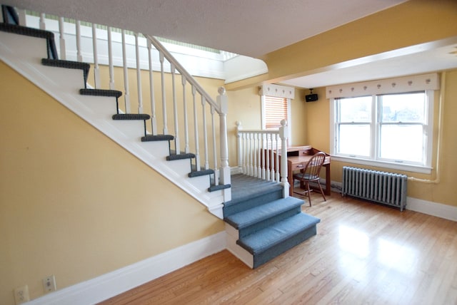 staircase featuring radiator heating unit and hardwood / wood-style floors