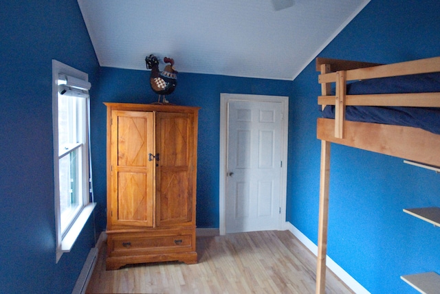 unfurnished bedroom featuring multiple windows, light hardwood / wood-style flooring, and vaulted ceiling