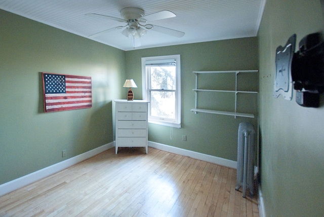 unfurnished bedroom with ceiling fan, light wood-type flooring, crown molding, and radiator