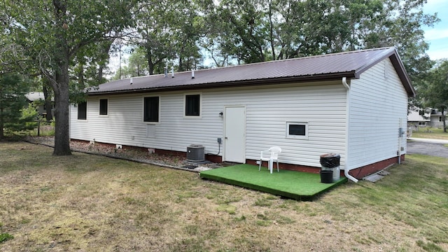 rear view of house featuring cooling unit and a yard