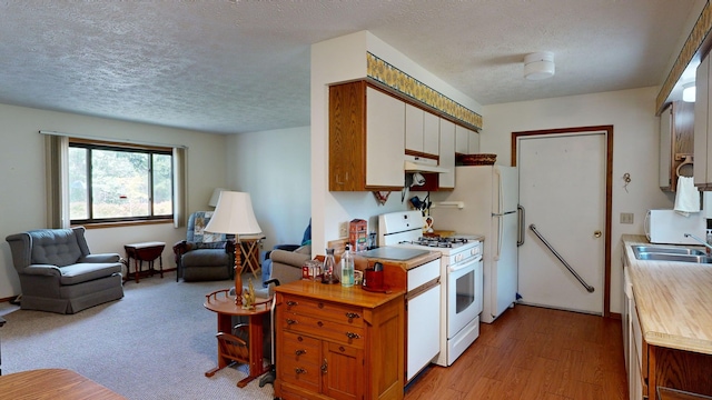 kitchen with light wood-type flooring, a textured ceiling, white appliances, and sink