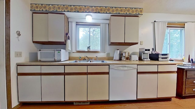 kitchen with a wealth of natural light, sink, light hardwood / wood-style floors, and white appliances