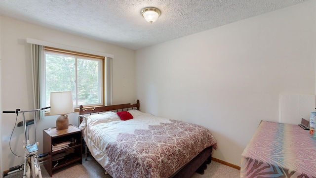 bedroom with a textured ceiling and light carpet