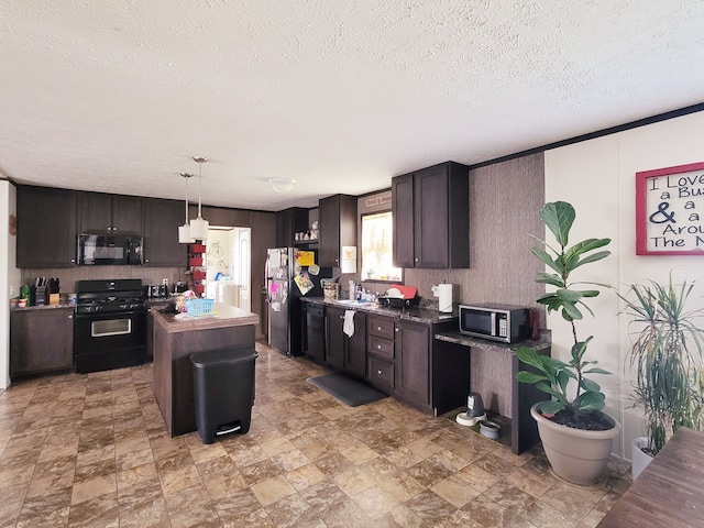 kitchen featuring pendant lighting, sink, dark brown cabinets, a center island, and black appliances