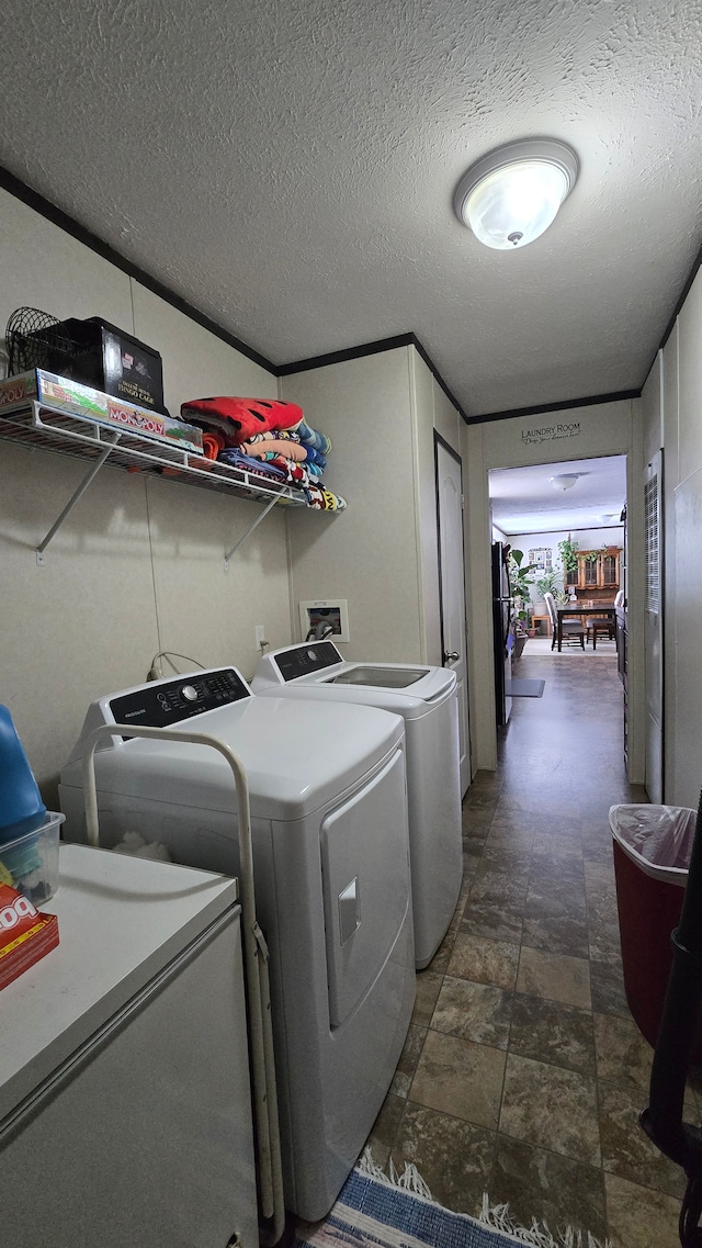 clothes washing area with washing machine and dryer, crown molding, and a textured ceiling