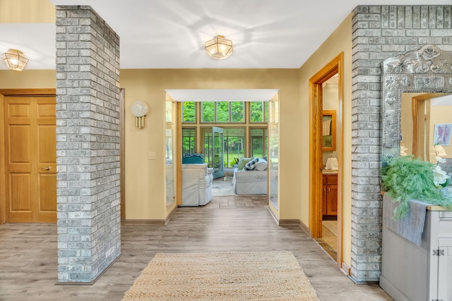 doorway to outside with decorative columns and light hardwood / wood-style flooring