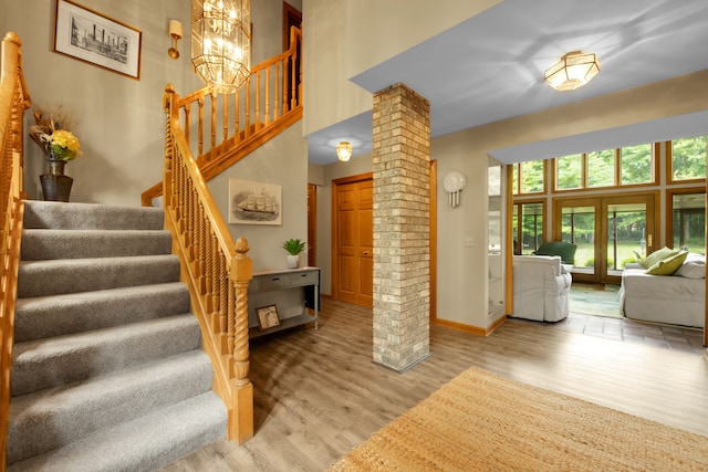 stairway with hardwood / wood-style flooring, a chandelier, french doors, and decorative columns