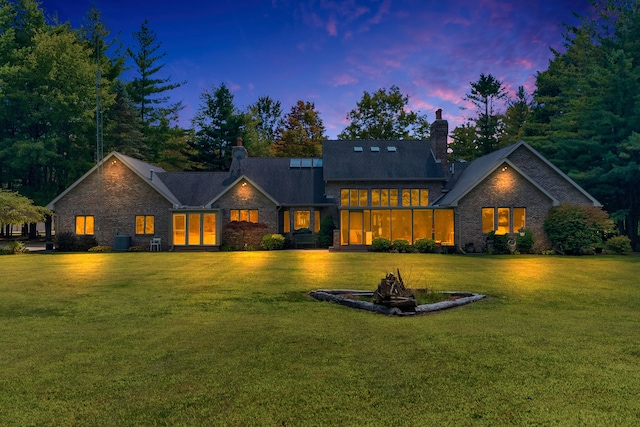 back house at dusk with a lawn, central air condition unit, and an outdoor fire pit