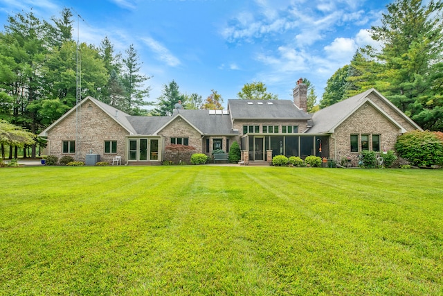 back of house featuring a lawn, a sunroom, and central AC unit