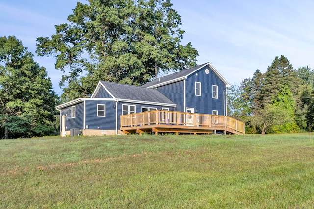 rear view of property featuring a lawn, central air condition unit, and a wooden deck