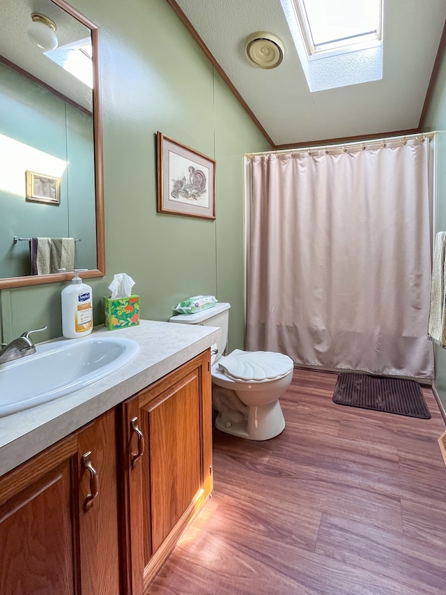 bathroom featuring a skylight, walk in shower, vanity, hardwood / wood-style flooring, and toilet