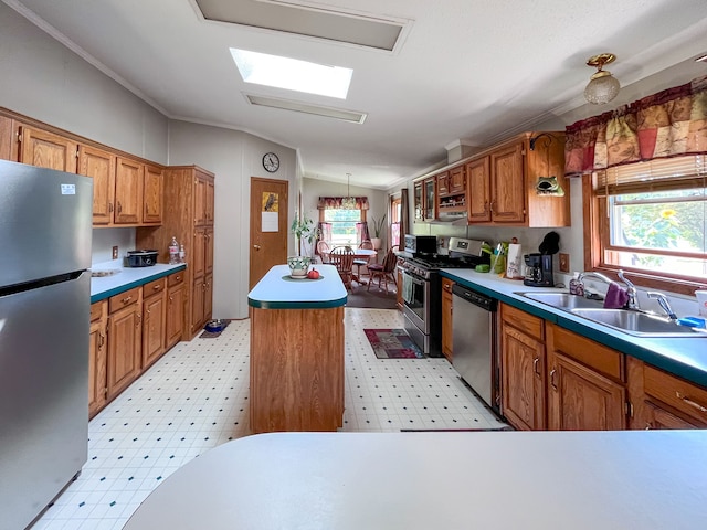 kitchen featuring appliances with stainless steel finishes, ornamental molding, lofted ceiling with skylight, sink, and a kitchen island