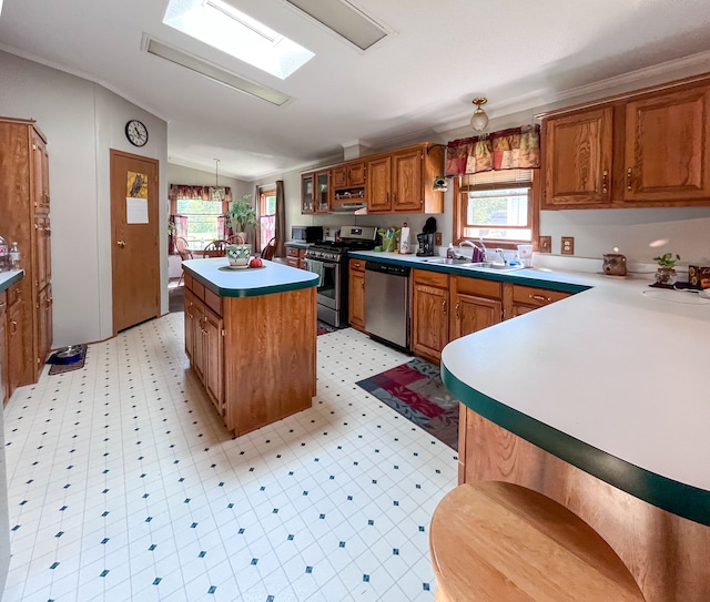 kitchen with appliances with stainless steel finishes, lofted ceiling with skylight, sink, a center island, and hanging light fixtures