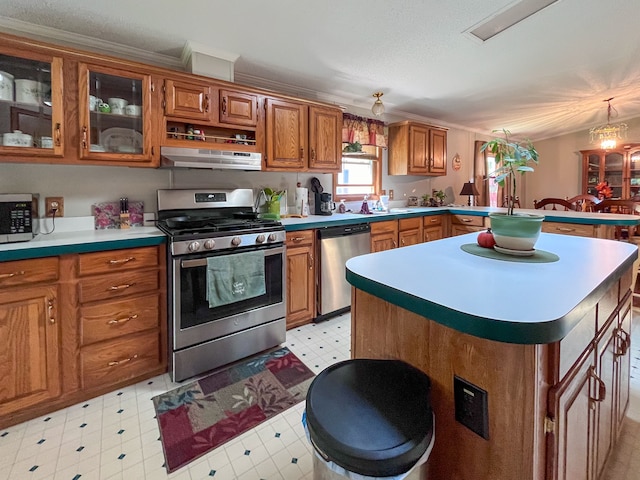 kitchen with stainless steel appliances, crown molding, a chandelier, pendant lighting, and a kitchen island