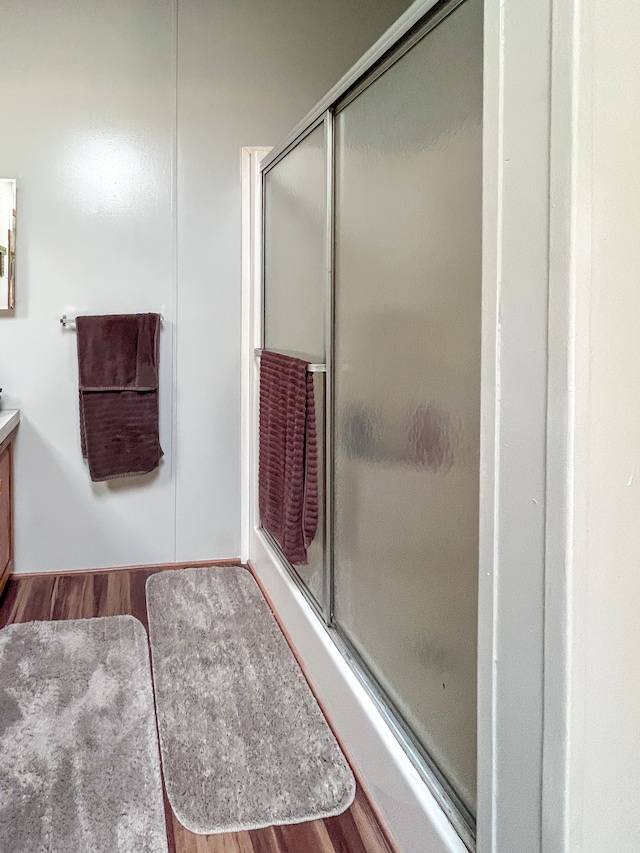 bathroom with hardwood / wood-style floors, vanity, and a shower with shower door