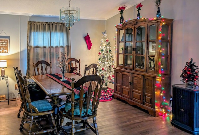 dining space with a chandelier, ornamental molding, and dark wood-type flooring