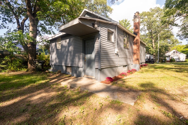 view of side of home with a lawn and a chimney