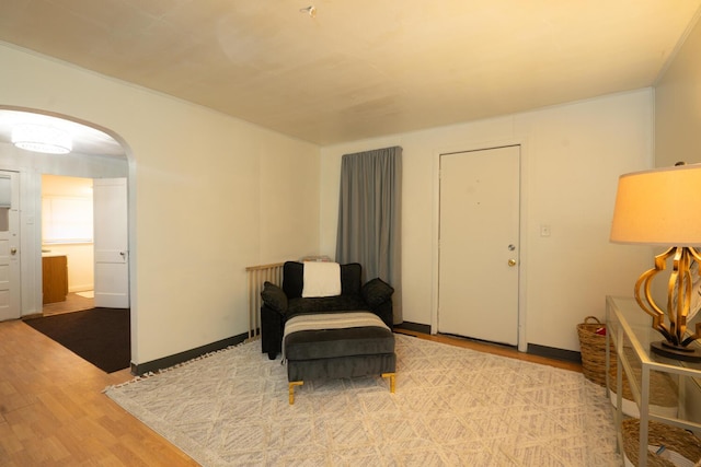 living area with baseboards, arched walkways, and wood finished floors